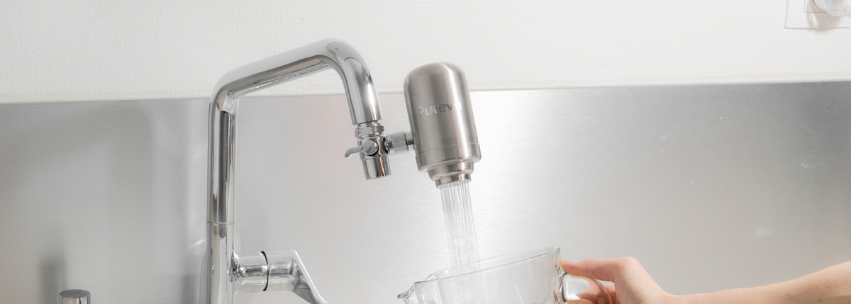 Filtre Pureva One installé sur un robinet, remplissant un verre d'eau
